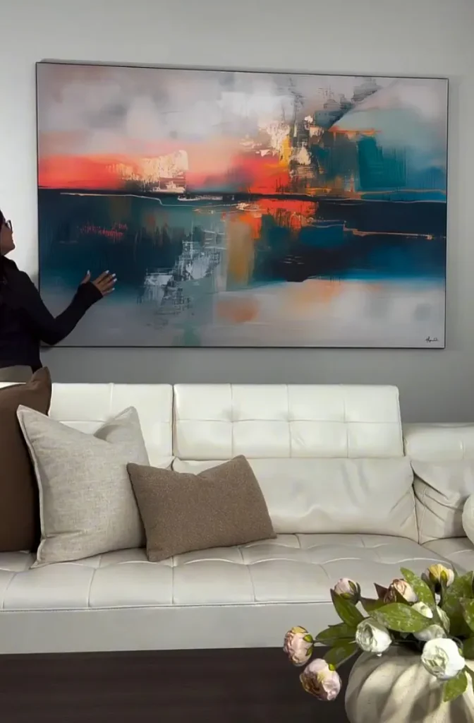 abstract wall art above a couch with a person beside